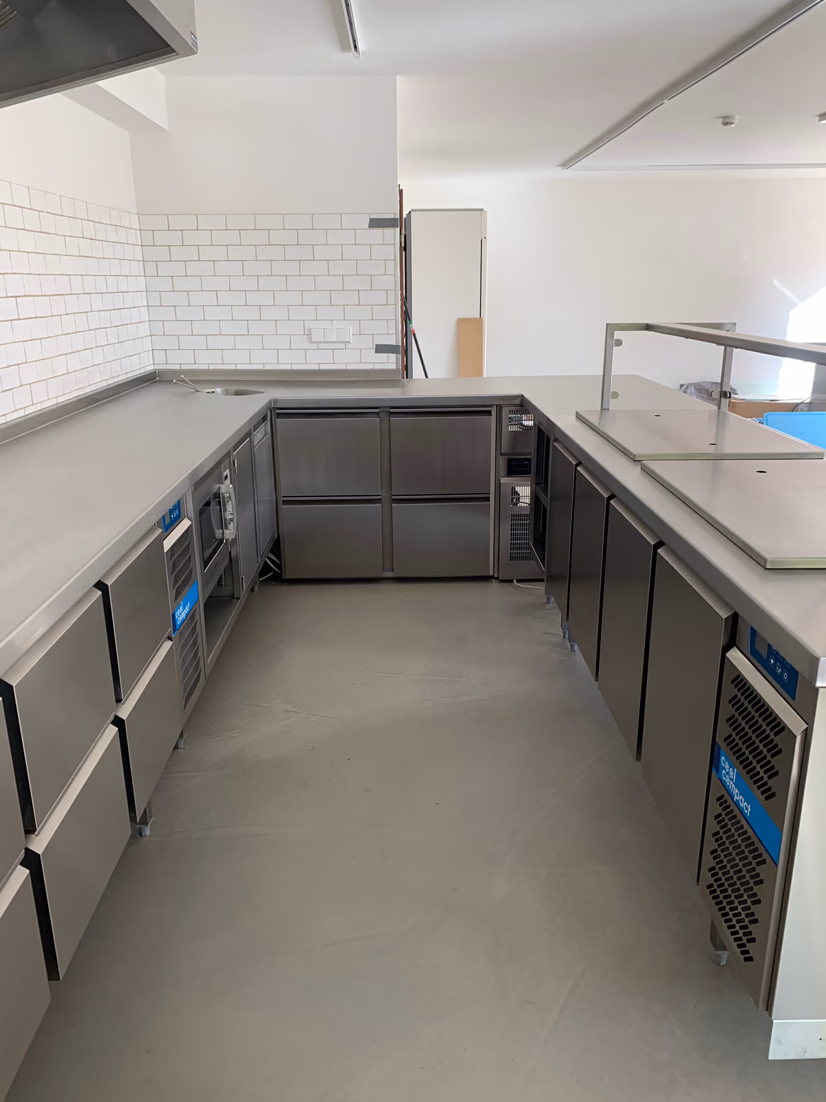 Edelstahl-Kühltische mit Schubladen und Unterbau-Kühlgeräten in einer Gewerbeküche