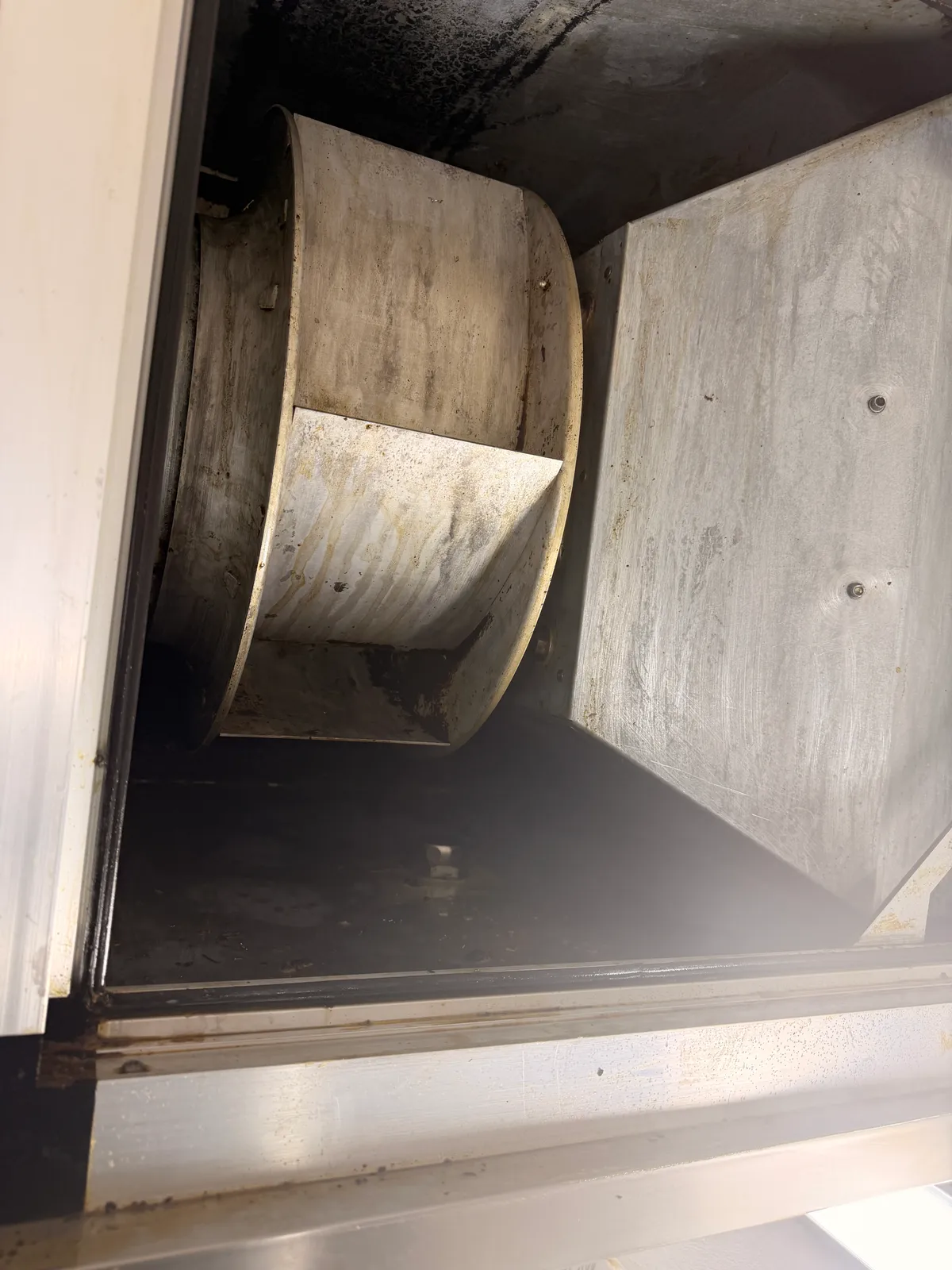 Ventilator und Innengehäuse derselben Küchenabluftanlage nach der Reinigung mit freigelegten Metallflächen